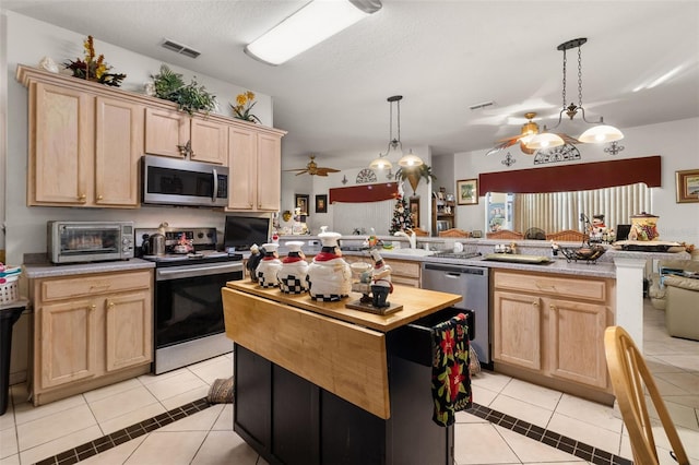 kitchen featuring kitchen peninsula, light brown cabinets, stainless steel appliances, and light tile patterned floors