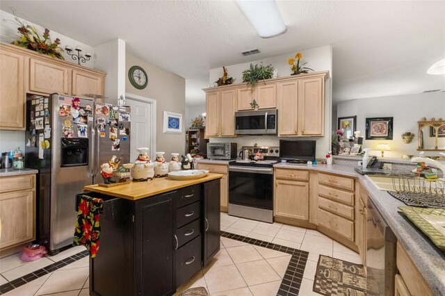 kitchen featuring light brown cabinets, sink, light tile patterned floors, a textured ceiling, and stainless steel appliances