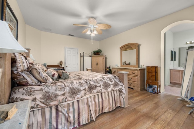 bedroom with ensuite bathroom, ceiling fan, and light wood-type flooring