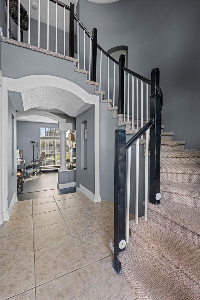 staircase with ornate columns and tile patterned flooring