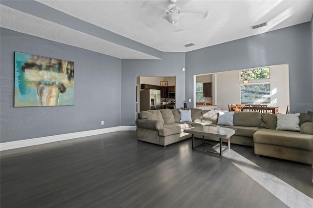 living room with ceiling fan, dark hardwood / wood-style flooring, and a textured ceiling