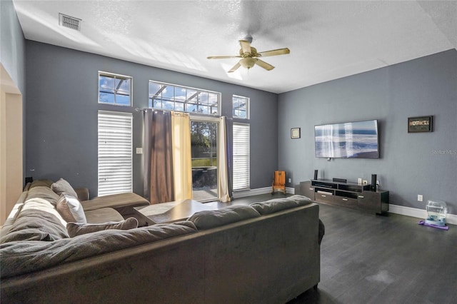 living room featuring ceiling fan, dark wood-type flooring, and a textured ceiling