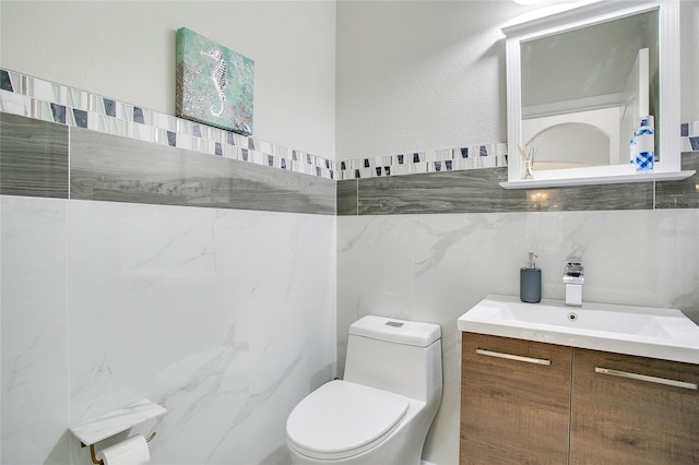 bathroom with vanity, toilet, and tile walls