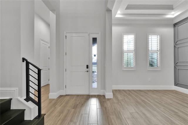 entryway featuring ornamental molding, light hardwood / wood-style floors, and a tray ceiling