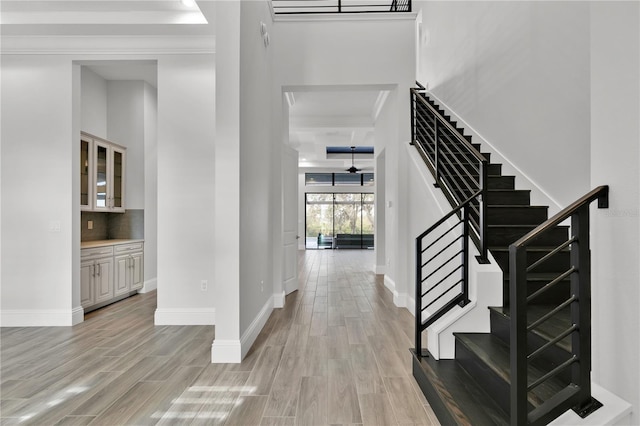 entrance foyer with beamed ceiling, light hardwood / wood-style floors, and crown molding