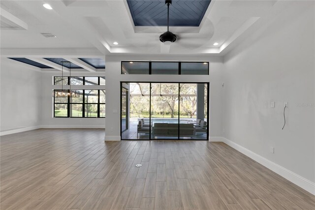 unfurnished room featuring hardwood / wood-style floors, ceiling fan with notable chandelier, and a tray ceiling