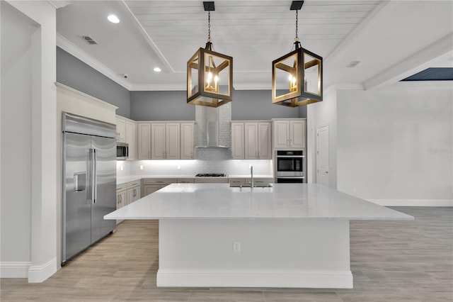 kitchen with a kitchen island with sink, hanging light fixtures, sink, light stone counters, and stainless steel appliances