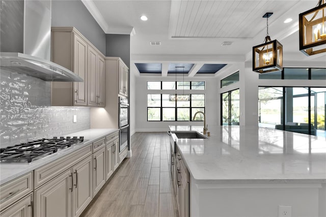 kitchen featuring light stone countertops, decorative light fixtures, wall chimney range hood, and appliances with stainless steel finishes