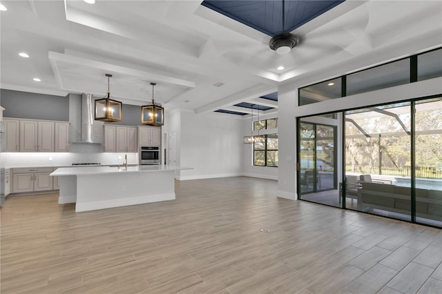 kitchen with stainless steel oven, a center island with sink, wall chimney exhaust hood, and light hardwood / wood-style floors