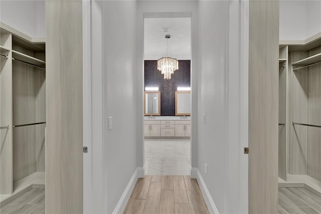 corridor with a notable chandelier and light hardwood / wood-style floors