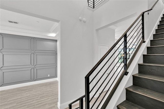 stairs featuring hardwood / wood-style flooring and crown molding