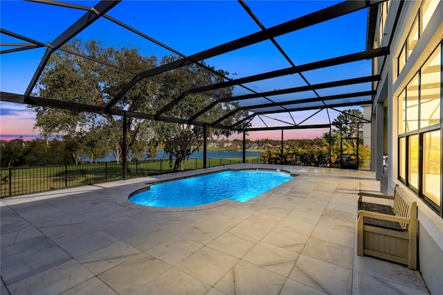 pool at dusk featuring glass enclosure and a patio area