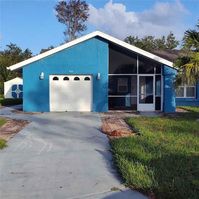 view of front facade with a garage, a storage shed, and a sunroom