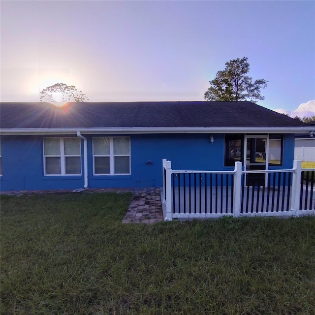 back house at dusk featuring a yard