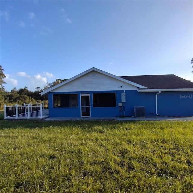 back of house featuring central AC unit and a yard