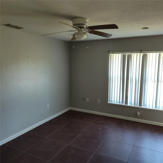 spare room featuring a textured ceiling, dark tile patterned floors, and ceiling fan