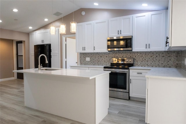 kitchen featuring white cabinets, vaulted ceiling, an island with sink, decorative light fixtures, and stainless steel appliances