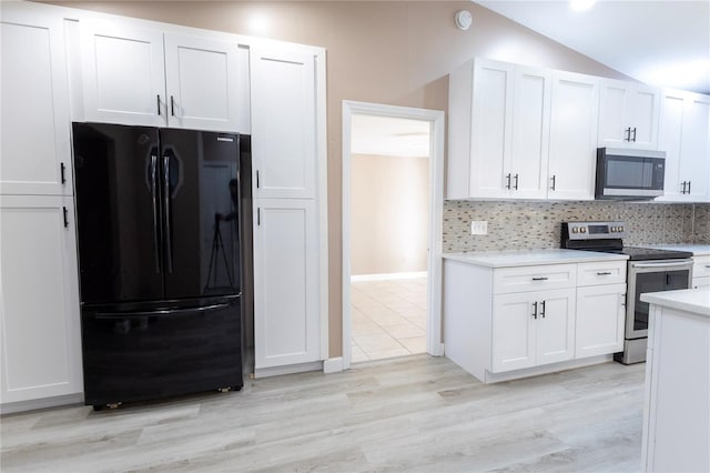 kitchen featuring tasteful backsplash, white cabinets, stainless steel appliances, and lofted ceiling