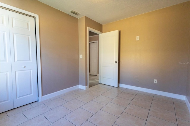 unfurnished bedroom featuring light tile patterned floors, a textured ceiling, and a closet