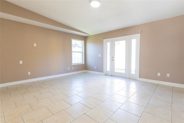 tiled empty room featuring lofted ceiling