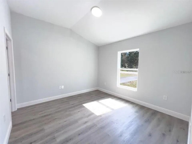 spare room with lofted ceiling and hardwood / wood-style flooring