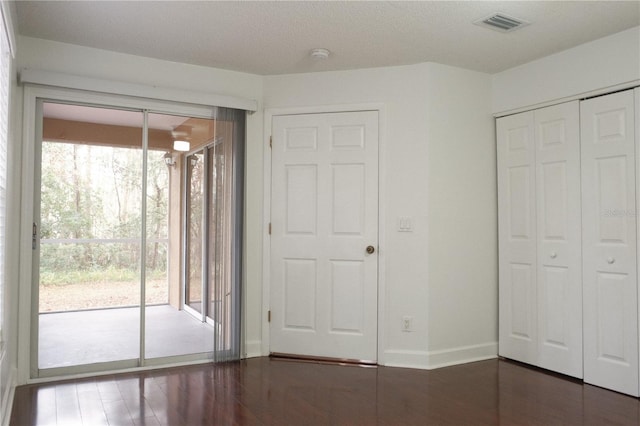 unfurnished bedroom with access to exterior and dark wood-type flooring