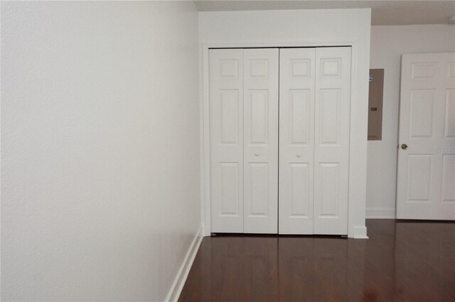 unfurnished bedroom with electric panel, a closet, and dark hardwood / wood-style flooring