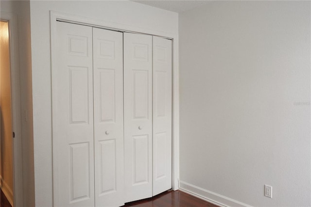 unfurnished bedroom with a closet and dark wood-type flooring