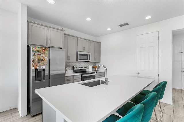 kitchen with a breakfast bar, a center island with sink, stainless steel appliances, and sink