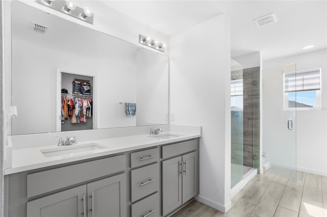 bathroom featuring hardwood / wood-style flooring, vanity, and a shower with door