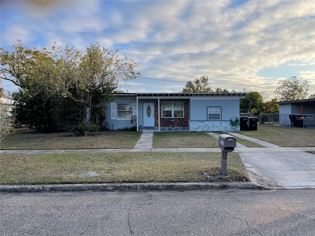 view of front facade with a front yard, stone siding, fence, and stucco siding