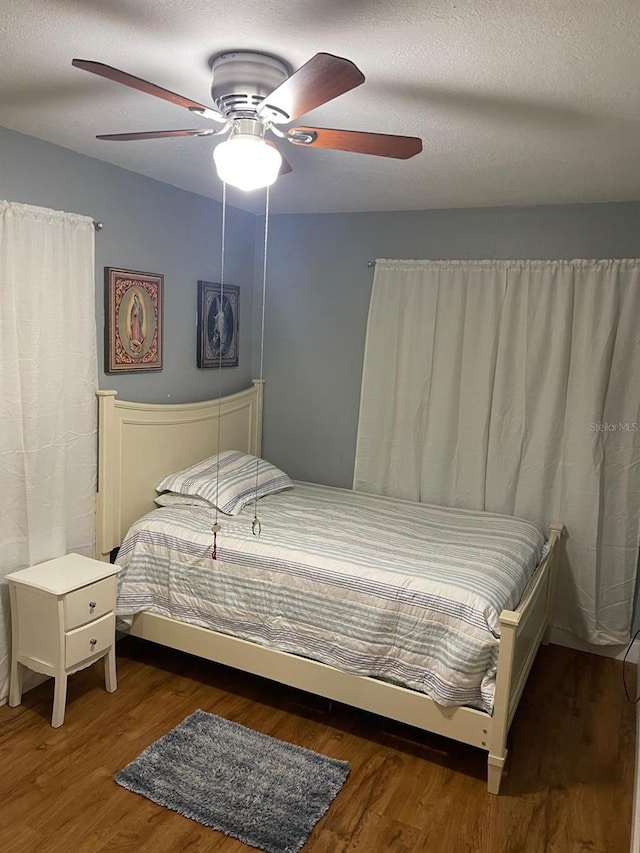 bedroom with ceiling fan, dark hardwood / wood-style flooring, and a textured ceiling