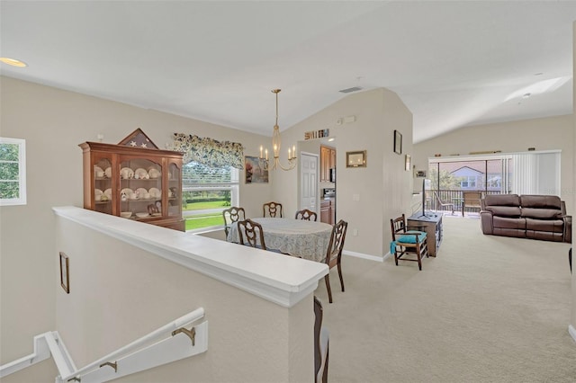 carpeted dining area featuring an inviting chandelier and vaulted ceiling