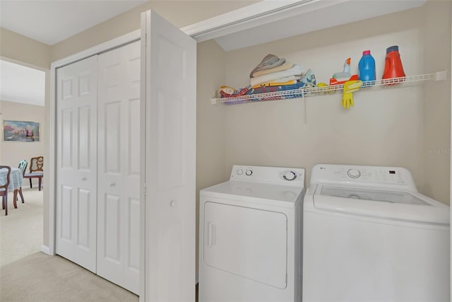 clothes washing area with separate washer and dryer and light carpet