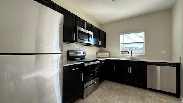 kitchen with sink, decorative backsplash, light tile patterned floors, a textured ceiling, and stainless steel appliances