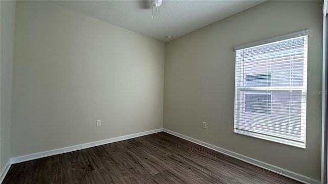 empty room featuring ceiling fan, dark wood-type flooring, and a textured ceiling