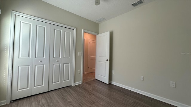 unfurnished bedroom with dark hardwood / wood-style floors, ceiling fan, a textured ceiling, and a closet