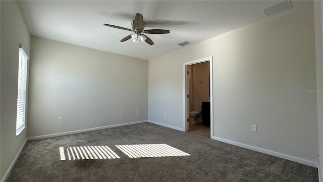 unfurnished room with dark colored carpet and ceiling fan