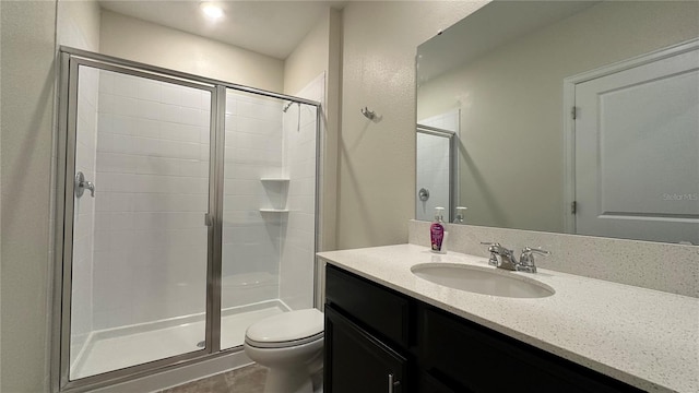 bathroom featuring vanity, toilet, and a shower with shower door