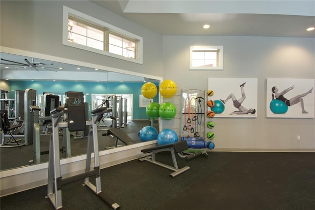 exercise room featuring ceiling fan, a wealth of natural light, and a high ceiling