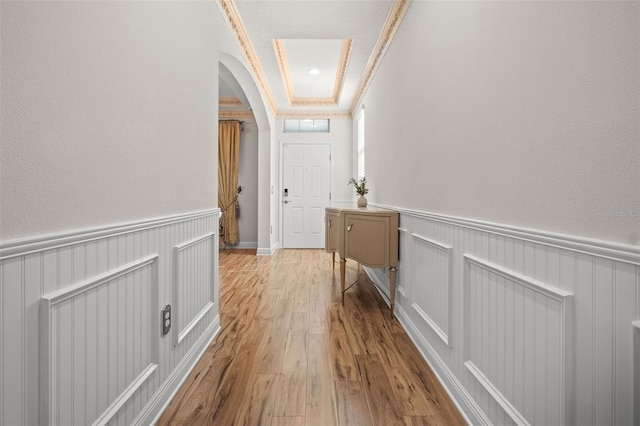 corridor with light wood-type flooring and crown molding