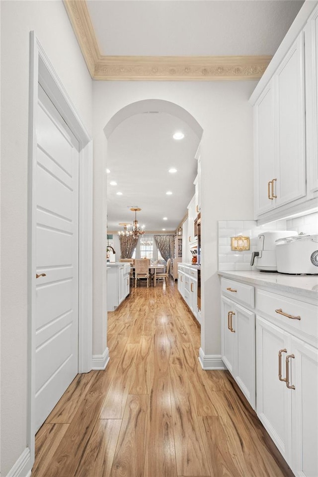 interior space featuring an inviting chandelier, crown molding, and light hardwood / wood-style flooring