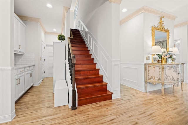 stairs featuring ornamental molding and hardwood / wood-style floors