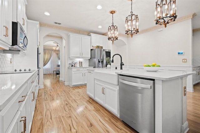 kitchen featuring stainless steel appliances, tasteful backsplash, decorative light fixtures, a kitchen island with sink, and white cabinets