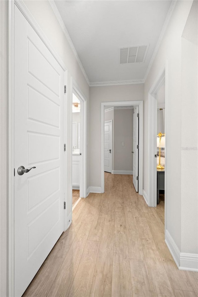 hallway with crown molding and light hardwood / wood-style floors