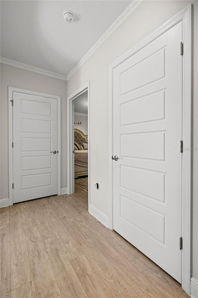 unfurnished bedroom featuring a textured ceiling, a closet, ornamental molding, and light wood-type flooring