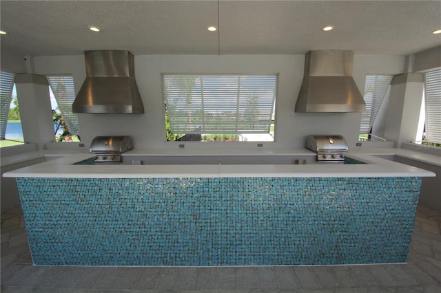 kitchen featuring wall chimney exhaust hood and kitchen peninsula