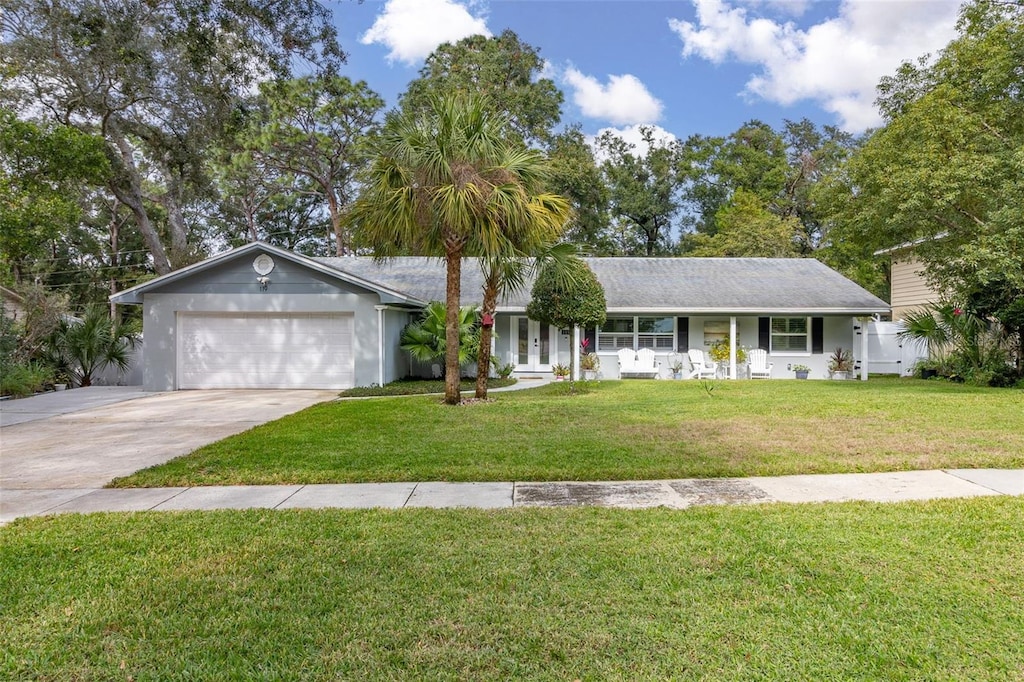 ranch-style house featuring a porch, a garage, and a front lawn