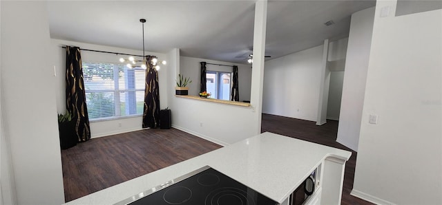 unfurnished dining area featuring ceiling fan with notable chandelier and dark hardwood / wood-style flooring