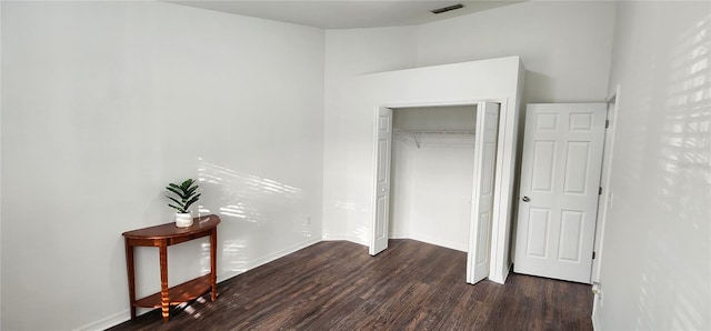 unfurnished bedroom featuring a closet and dark wood-type flooring